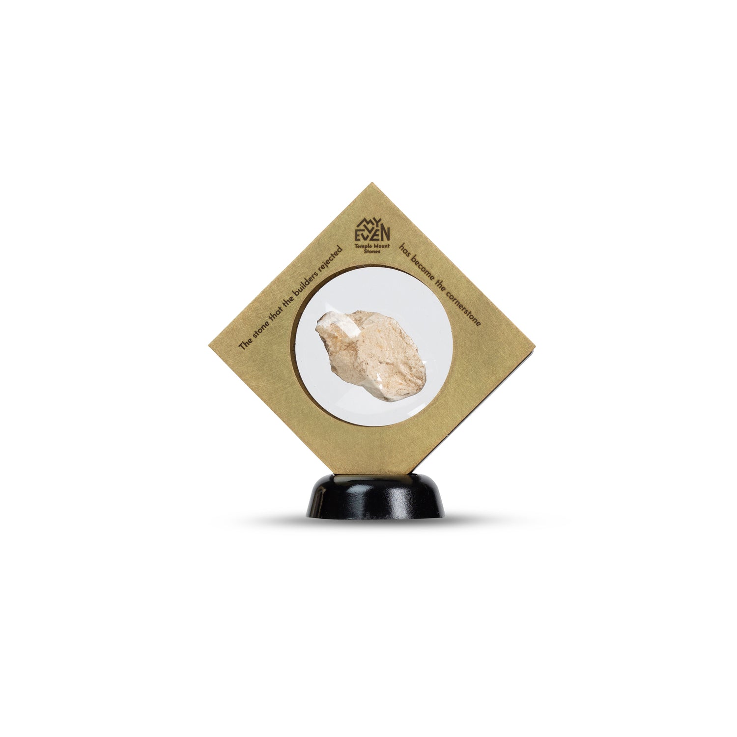 A natural stone is suspended in the middle of a square bronze frame that is set on a round black stand in a diamond position. On the tip of the Diamond is the "MyEvven" logo that says Temple Mount Stones below it. On the top left side of the frame, it reads "The stone that the builders rejected". On the top right side of the frame, it finishes quote "has become the cornerstone".