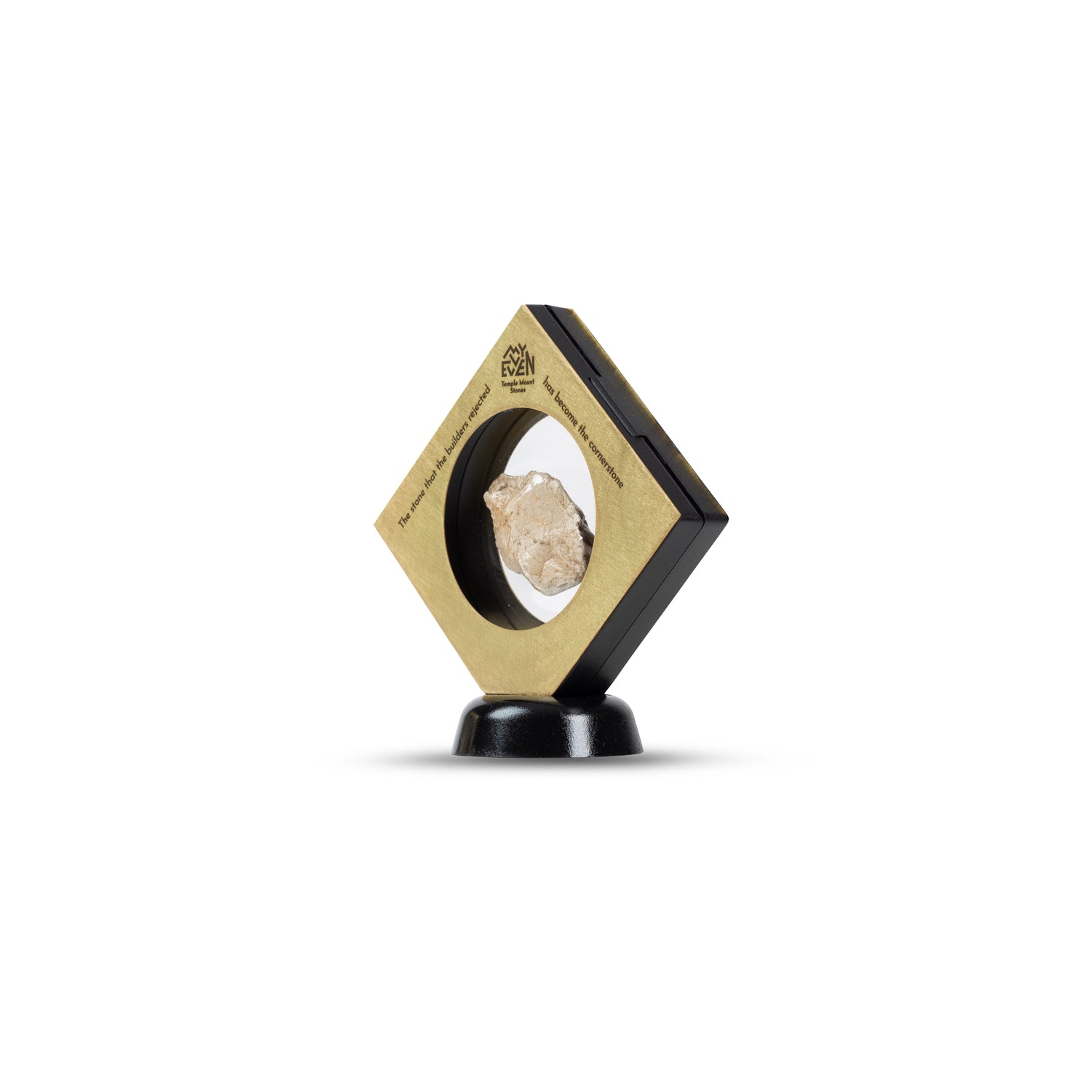 A side view of a natural stone suspended in the middle of a square bronze frame that is set on a round black stand in a diamond position. On the tip of the Diamond is the "MyEvven" logo that says Temple Mount Stones below it. On the top left side of the frame, it reads "The stone that the builders rejected". On the top right side of the frame, it finishes quote "has become the cornerstone".