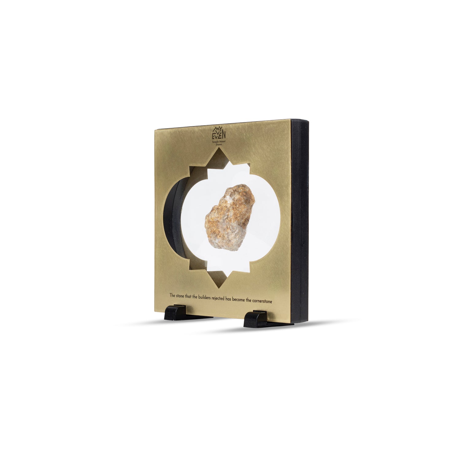 A side view of a natural stone suspended in the middle of a square bronze frame with a traditional middle eastern inlay that is set on two little black square stands. On the top of the frame is the "MyEvven" logo that says Temple Mount Stones below it. On the bottom of the frame, it reads "The stone that the builders rejected has become the cornerstone".