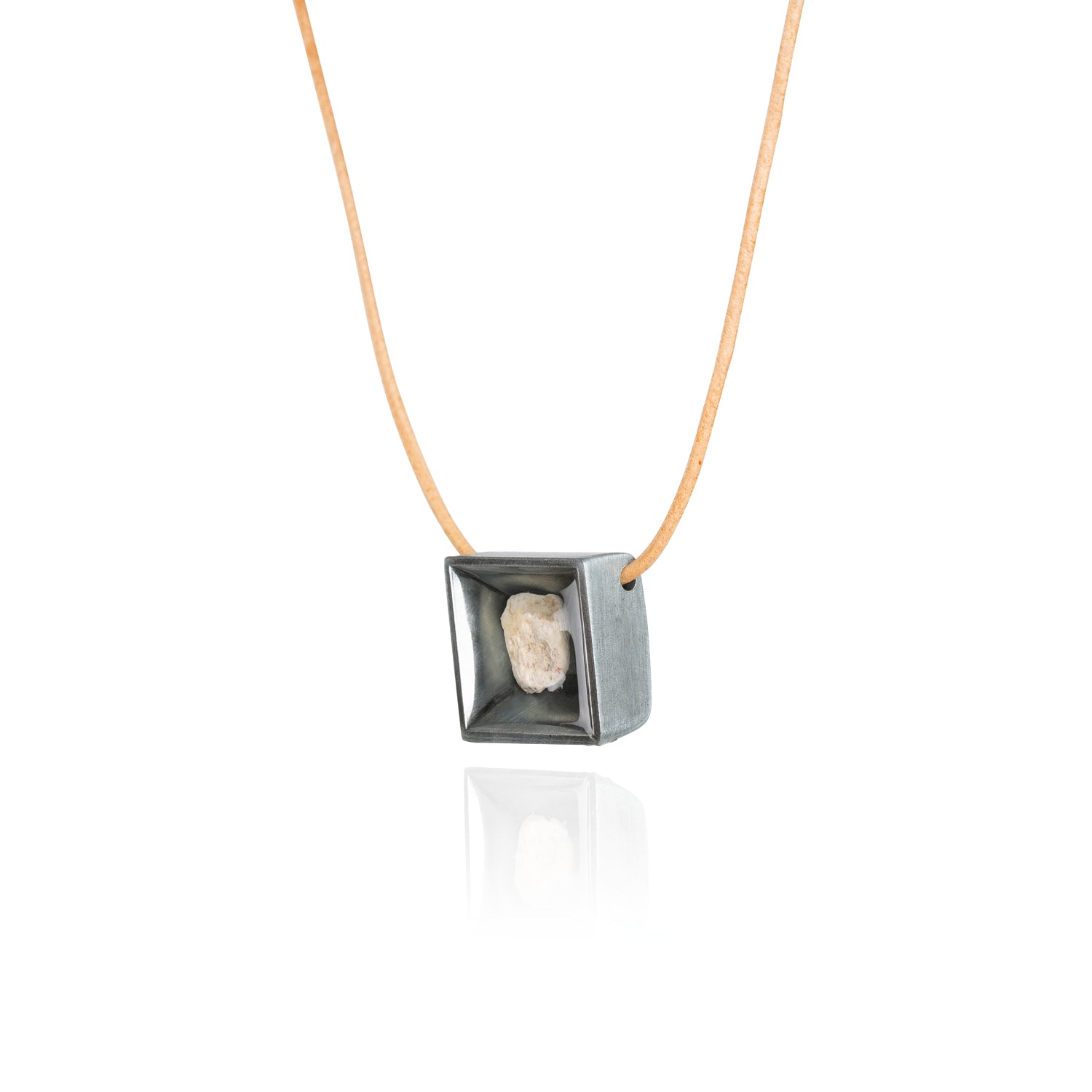 A side view of a small natural tan stone sitting in the middle of a square shaped metal pendant in a dark silver color. The pendant is hanging on a tan leather necklace.