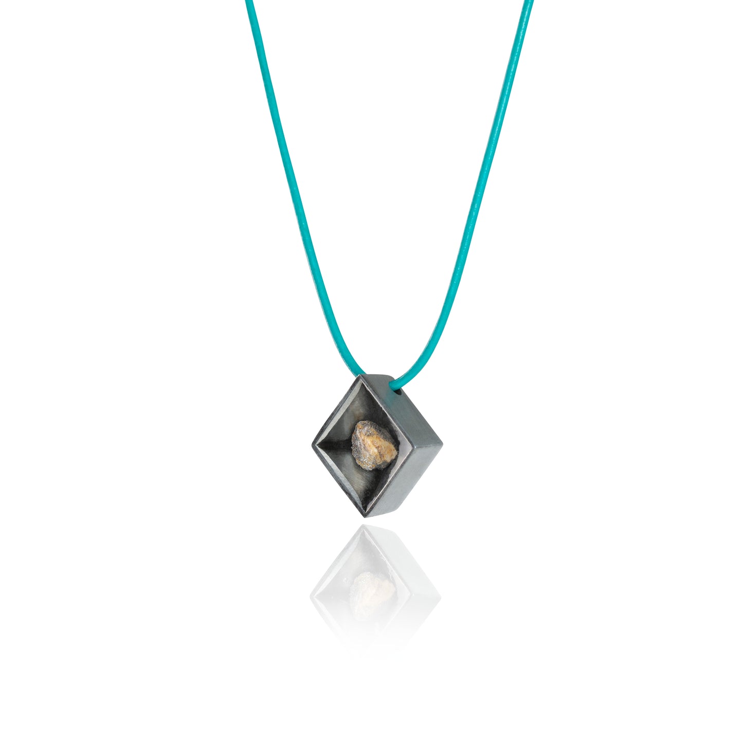 A side view of a small natural multicolored stone siting in the middle of a diamond shaped metal pendant in a dark silver color. The pendant is hanging on a turquoise leather necklace.