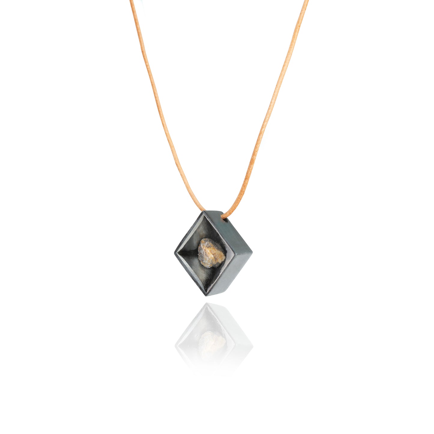 A side view of a small natural multicolored stone sitting in the middle of a diamond shaped metal pendant in a dark silver color. The pendant is hanging on a tan leather necklace.