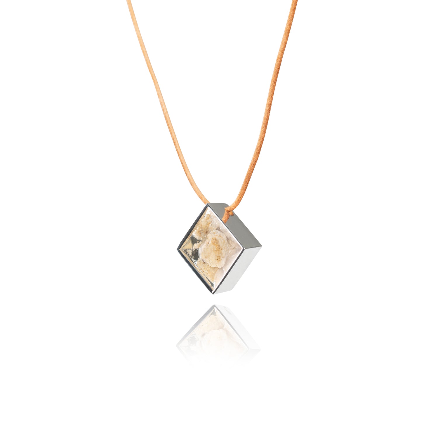 A side view of a small natural tan stone sitting in the middle of a diamond shaped metal pendant in a silver color. The pendant is hanging on a tan leather necklace.