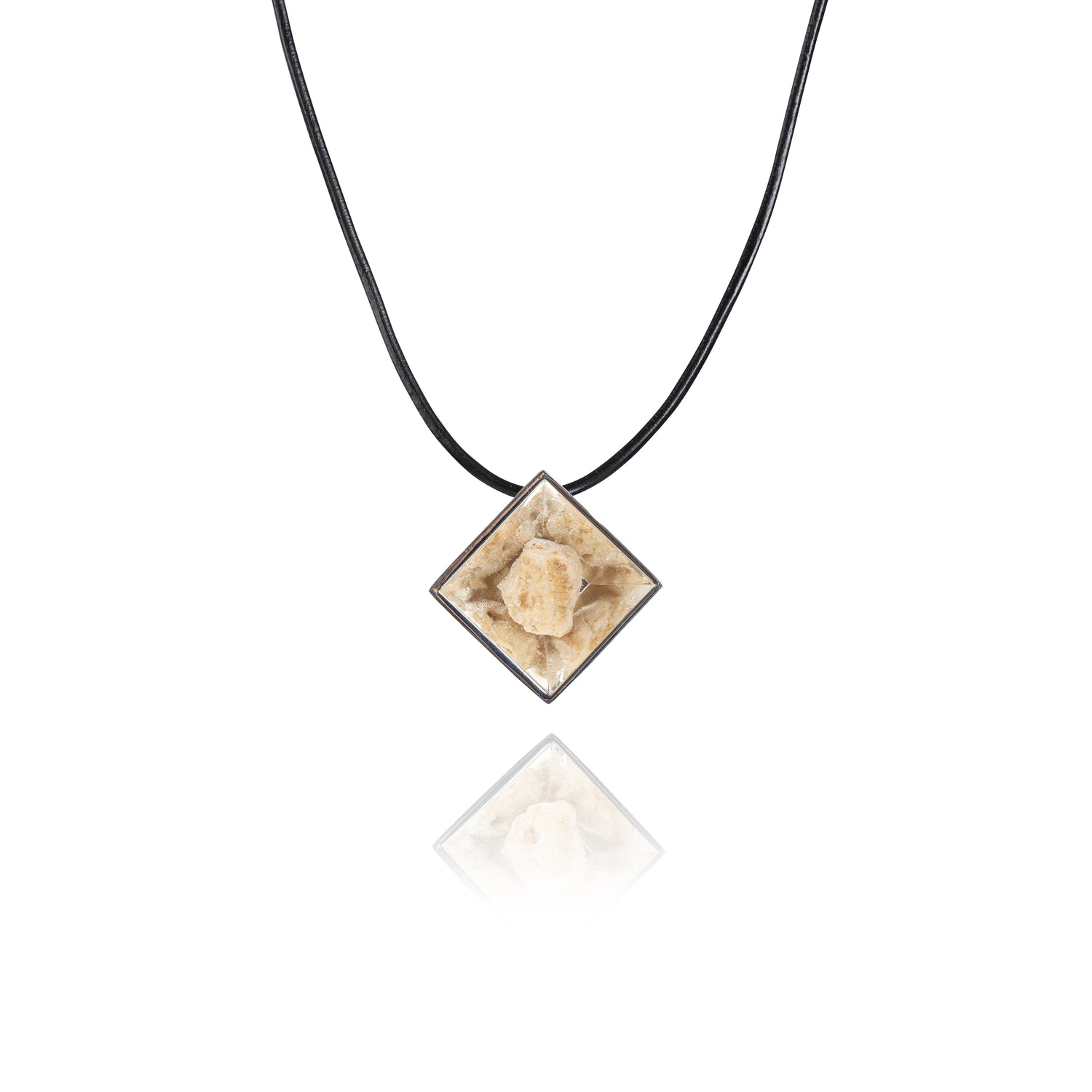 A small natural tan stone sitting in the middle of a diamond shaped metal pendant in a silver color. The pendant is hanging on a black leather necklace.