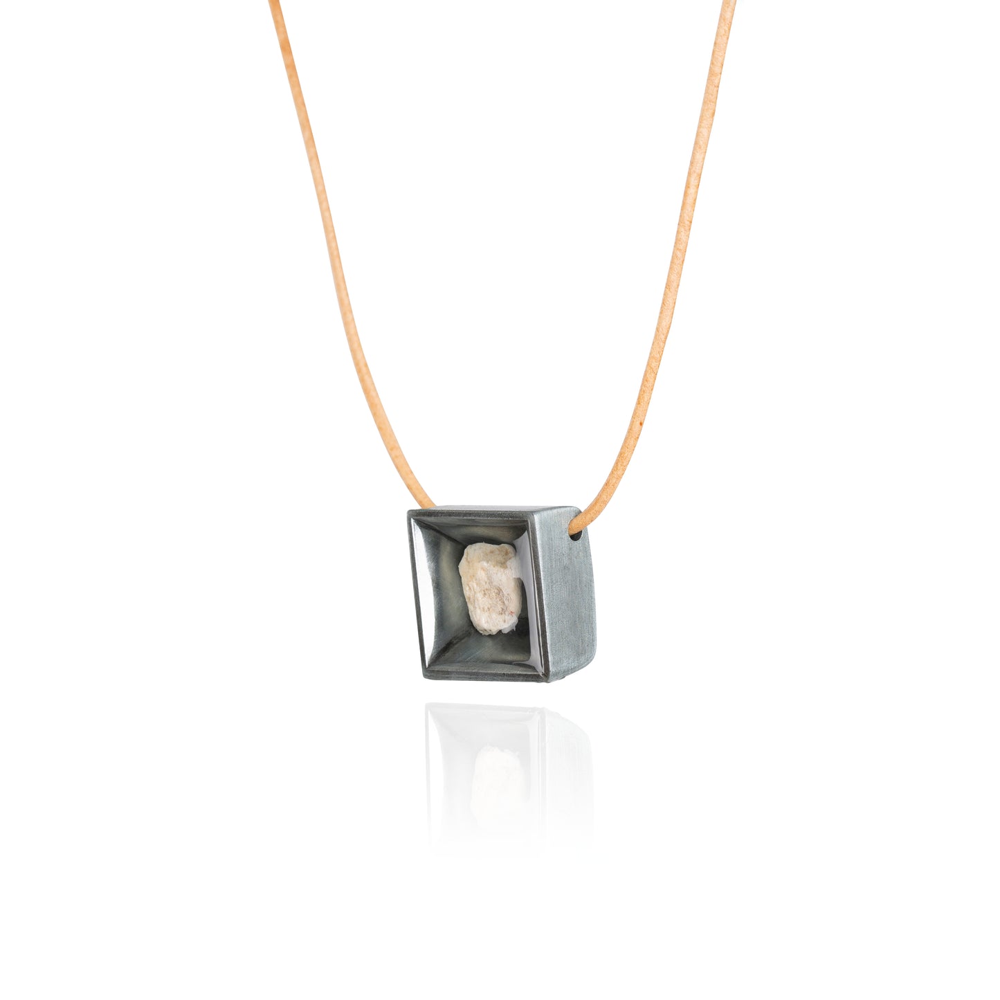 A side view of a small natural tan stone sitting in the middle of a square shaped metal pendant in a dark silver color. The pendant is hanging on a tan leather necklace.