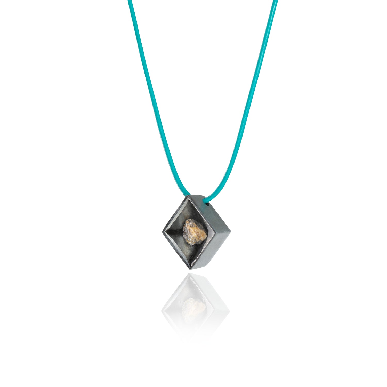 A side view of a small natural multicolored stone siting in the middle of a diamond shaped metal pendant in a dark silver color. The pendant is hanging on a turquoise leather necklace. 