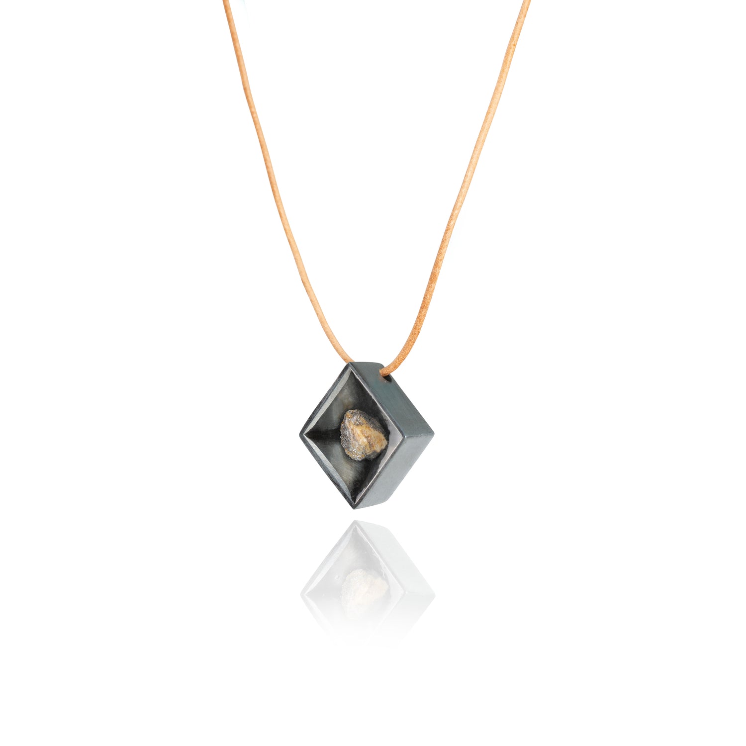 A side view of a small natural multicolored stone sitting in the middle of a diamond shaped metal pendant in a dark silver color. The pendant is hanging on a tan leather necklace. 