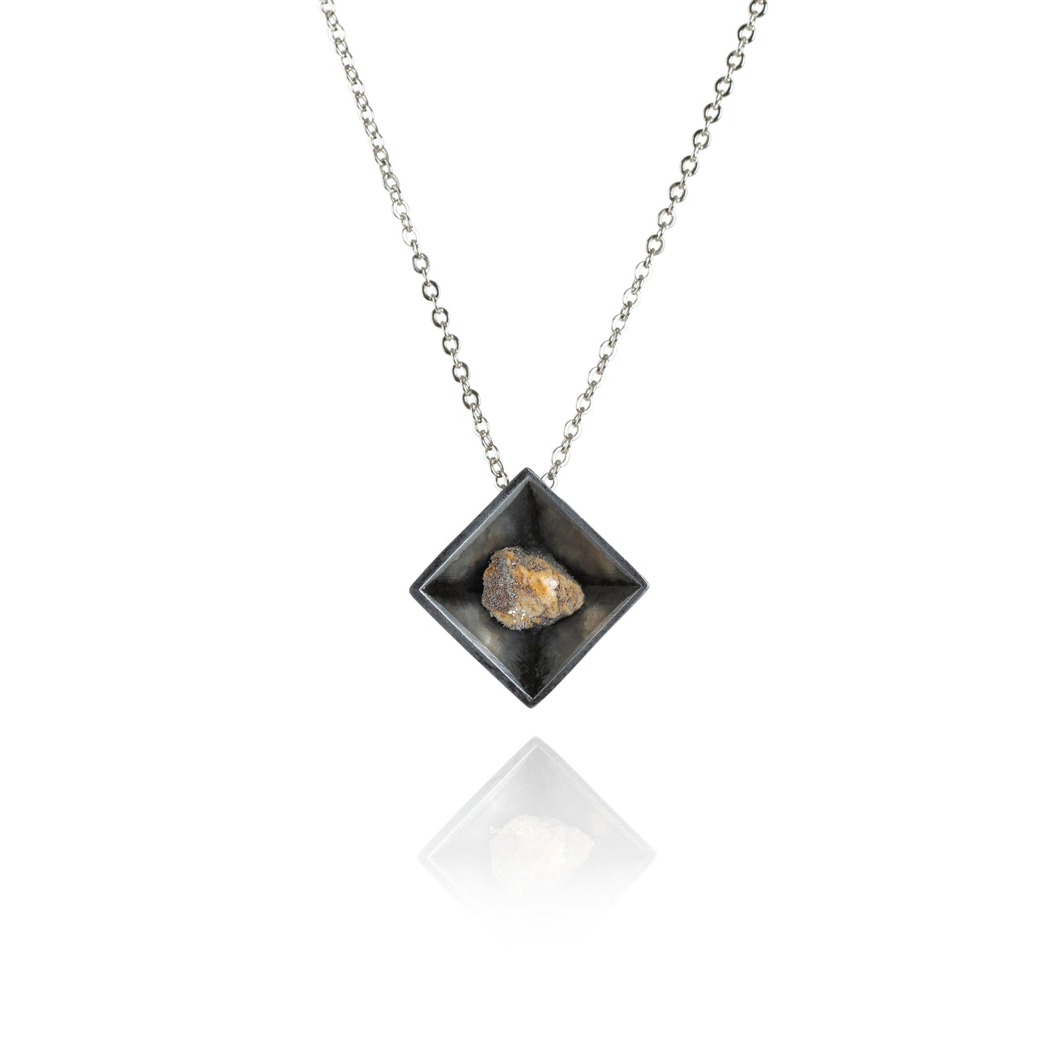 A small natural multicolored stone sitting in the middle of a diamond shaped metal pendant in a dark silver color. The pendant is hanging on silver chain.