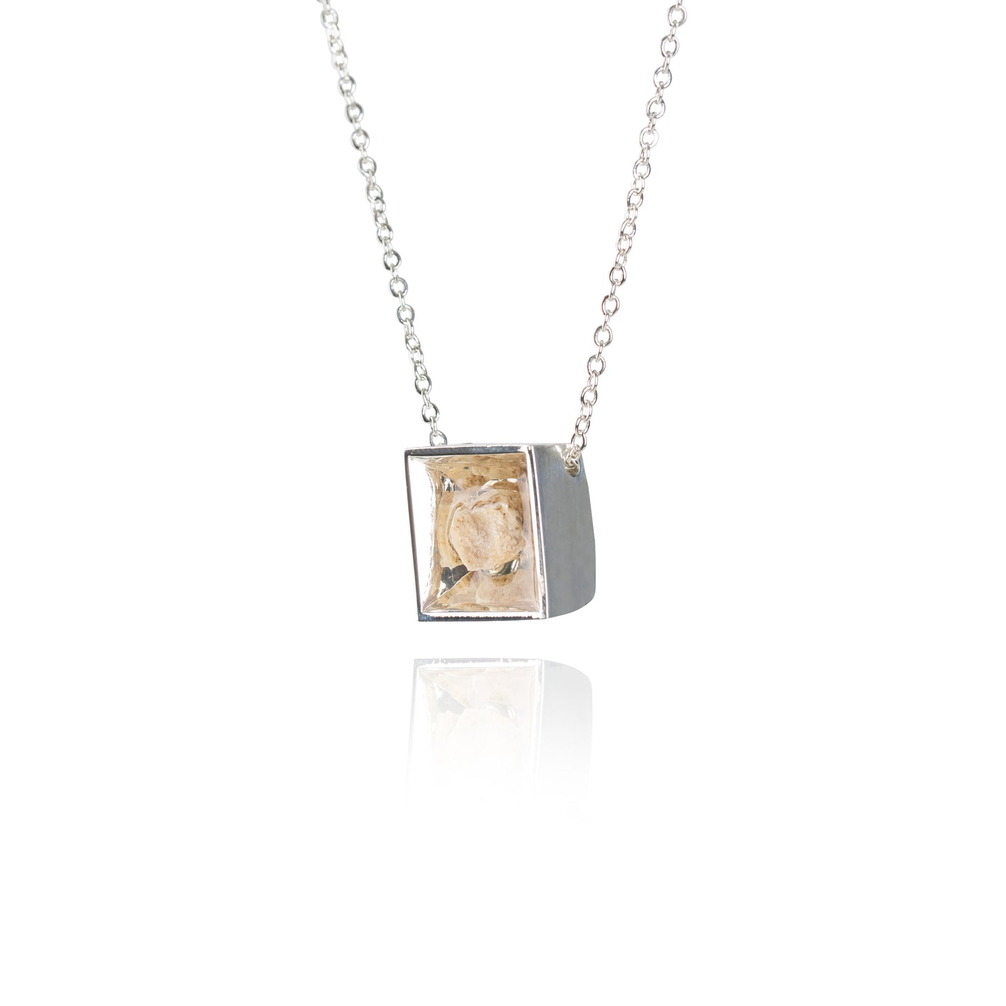 A side view of a small natural tan stone sitting in the middle of a square shaped metal pendant in a silver color. The pendant is hanging on a silver chain.
