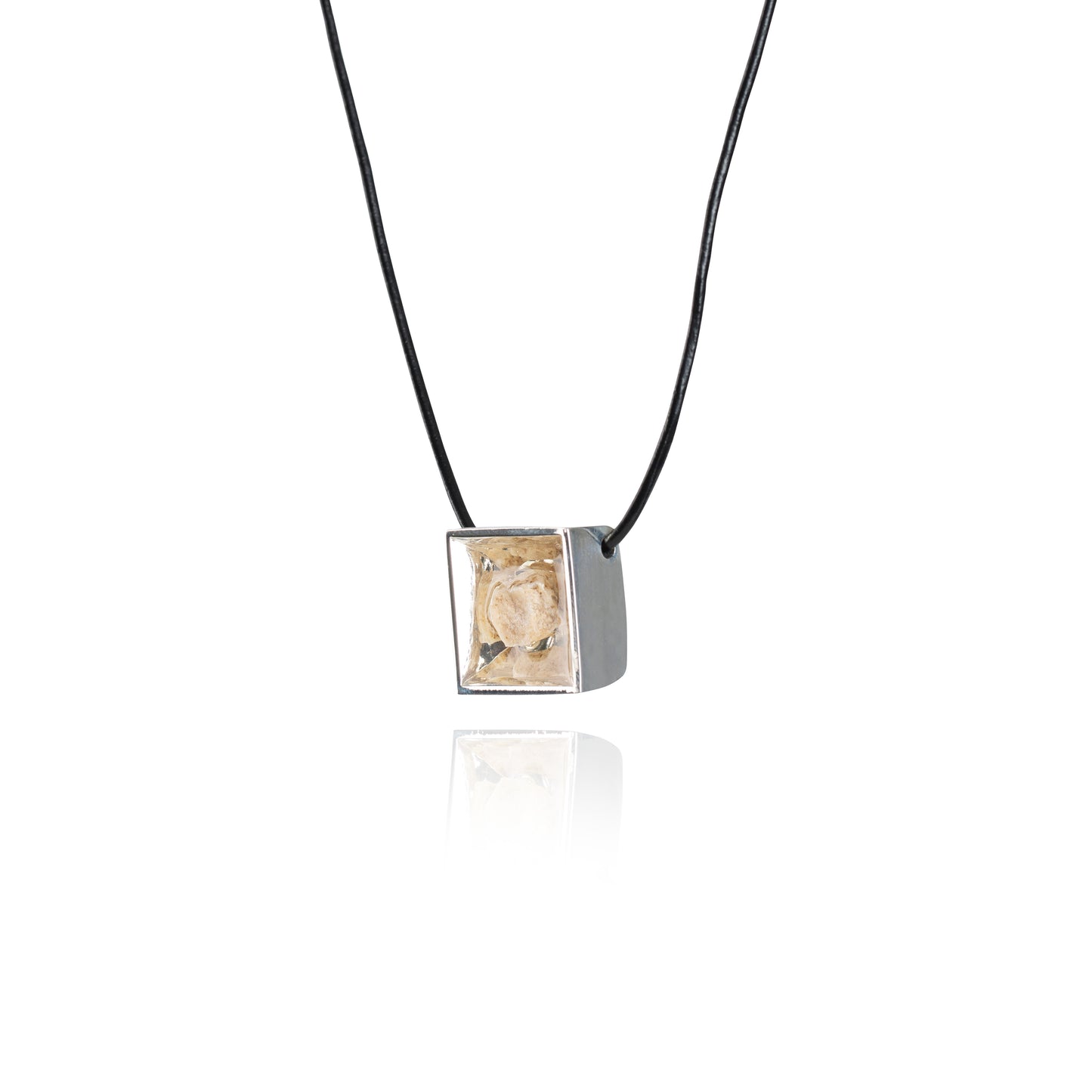 A side view of a small natural tan stone sitting in the middle of a square shaped metal pendant in a silver color. The pendant is hanging on a black leather necklace.