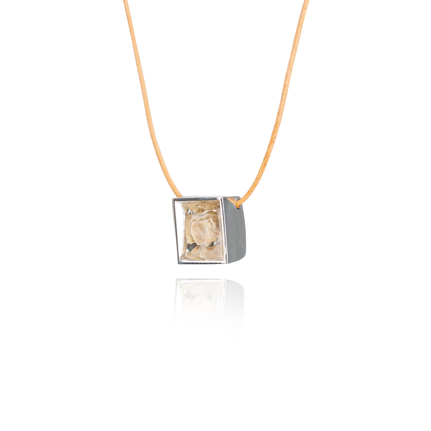 A side view of a small natural tan stone sitting in the middle of a square shaped metal pendant in a silver color. The pendant is hanging on a tan leather necklace.