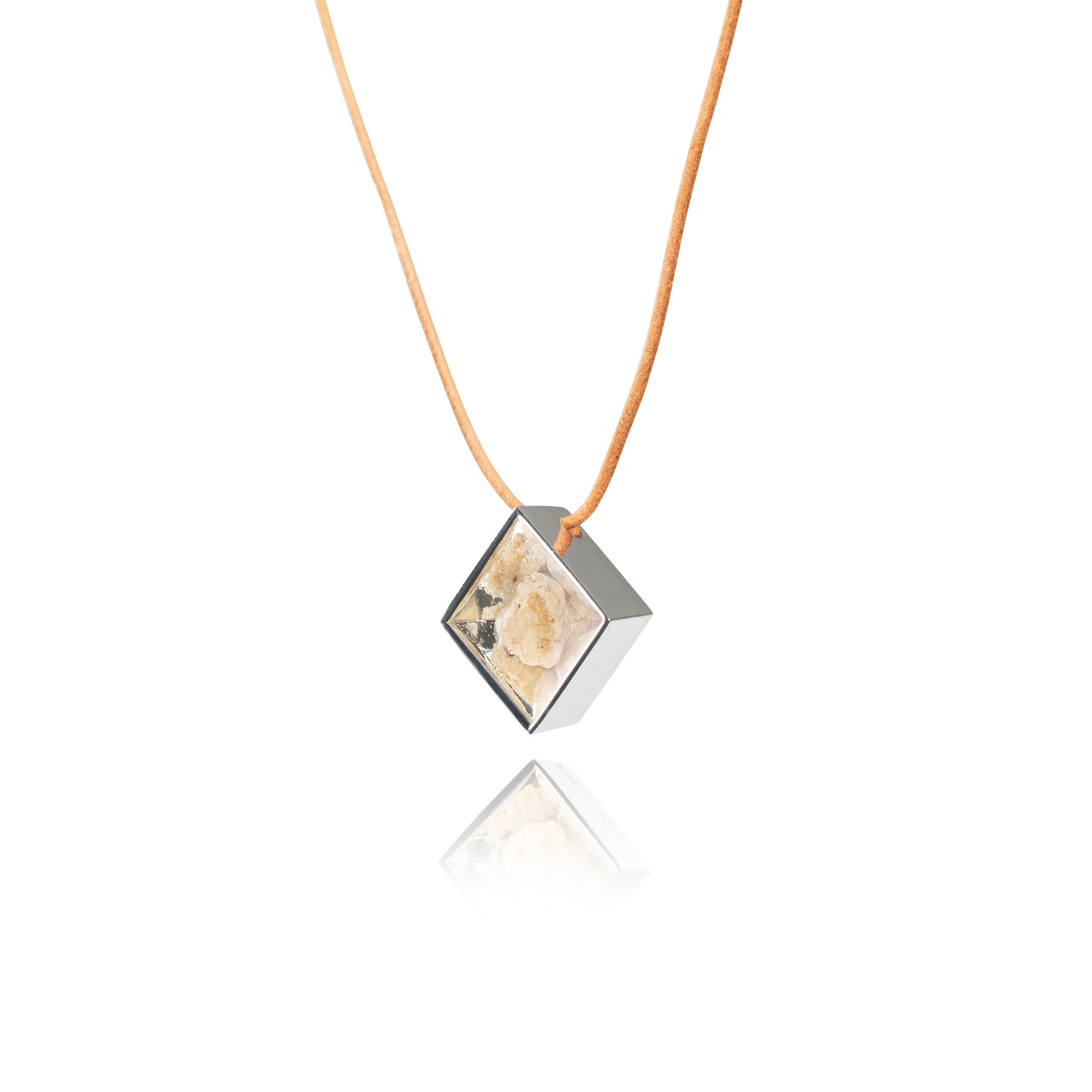 A side view of a small natural tan stone sitting in the middle of a diamond shaped metal pendant in a silver color. The pendant is hanging on a tan leather necklace.