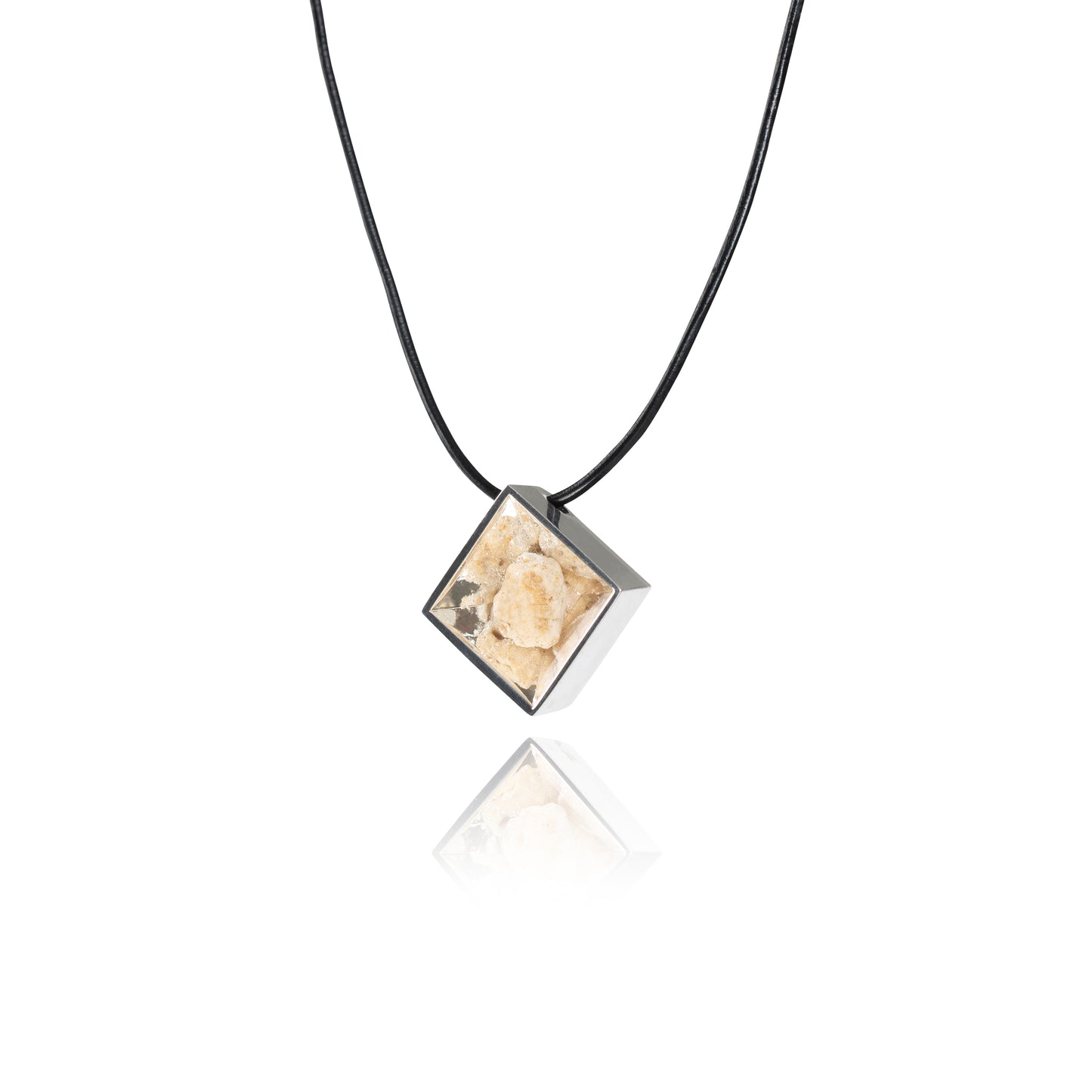 A side view of a small natural tan stone sitting in the middle of a diamond shaped metal pendant in a silver color. The pendant is hanging on a black leather necklace.