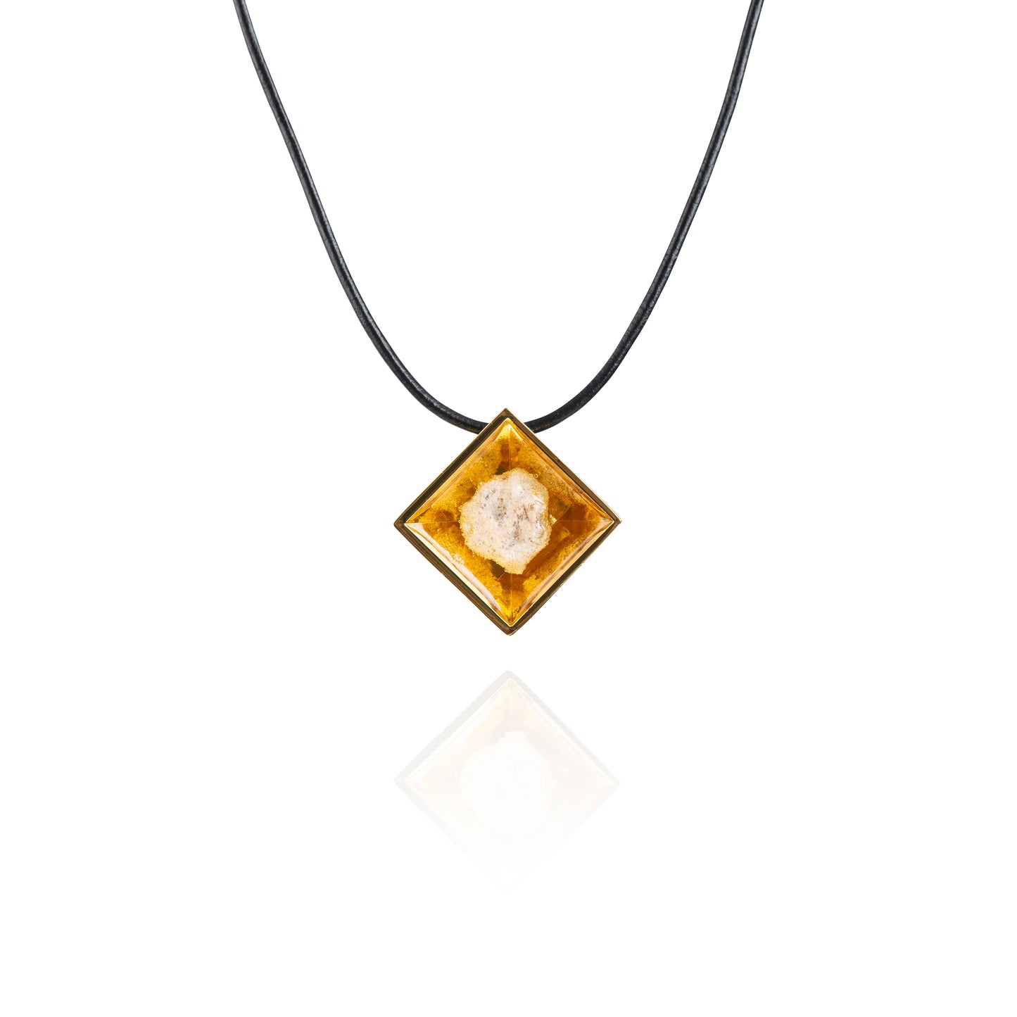 A small natural tan stone sitting in the middle of a diamond shaped metal pendant in a gold color. The pendant is hanging on a black leather necklace.