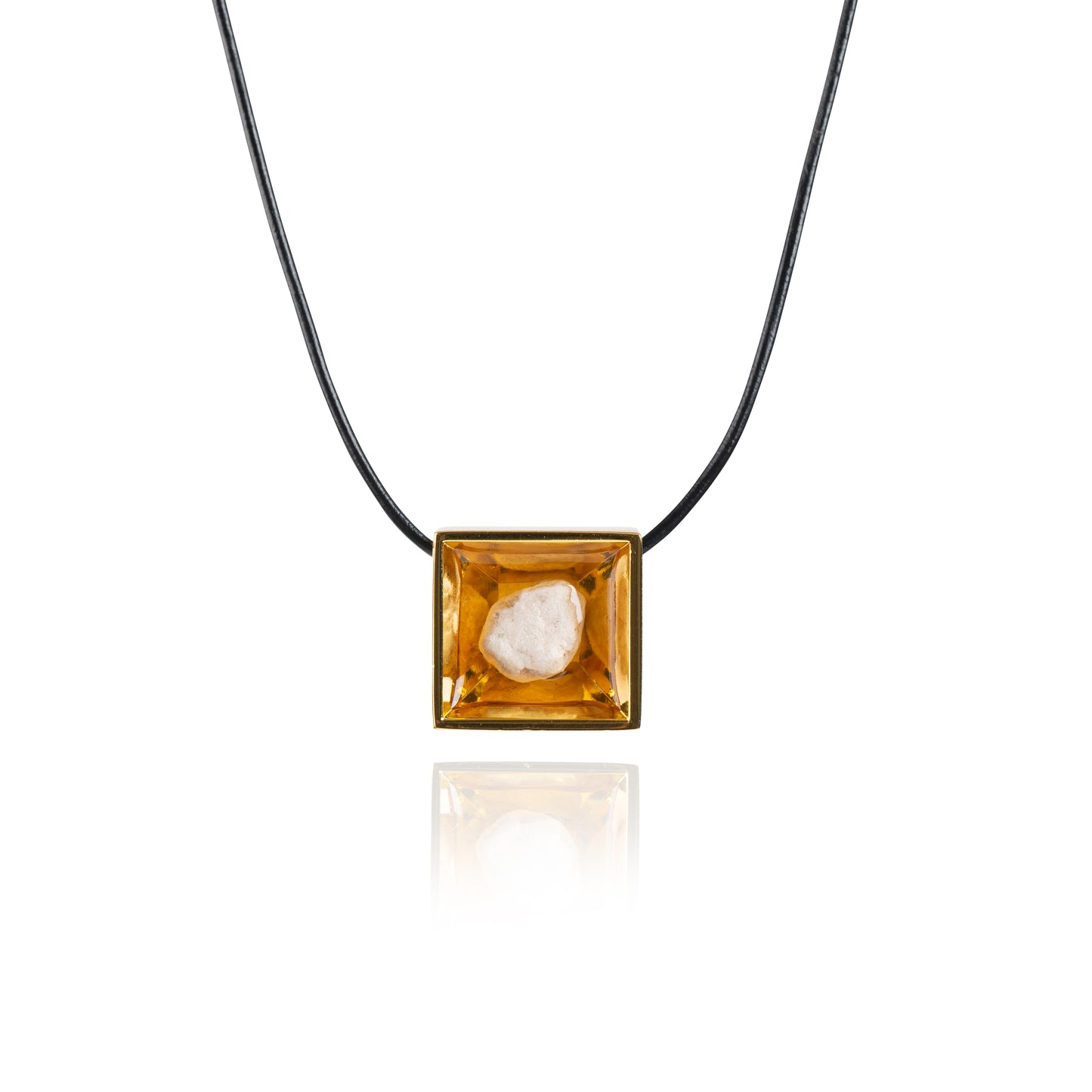 A small natural tan stone sitting in the middle of a square shaped metal pendant in a gold color. The pendant is hanging on a black leather necklace.