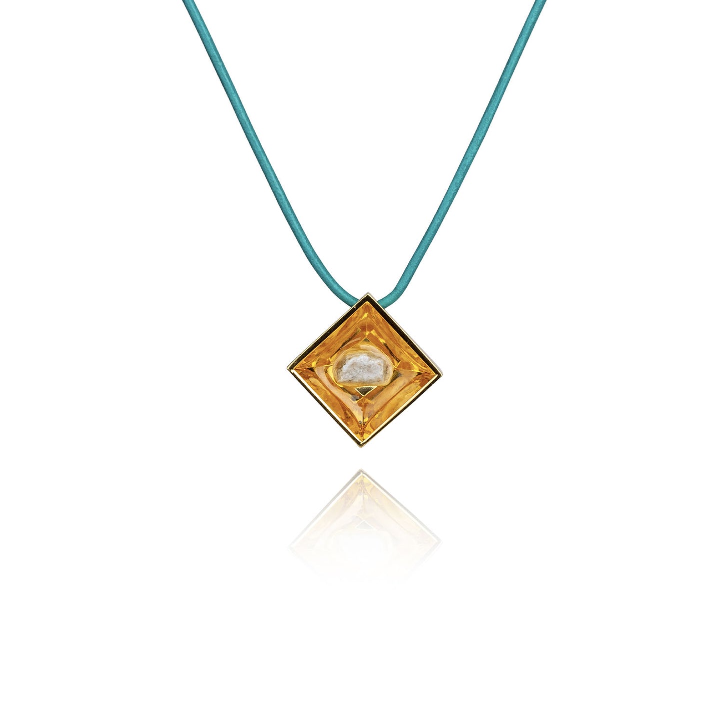 A small natural tan stone sitting in the middle of a diamond shaped metal pendant in a gold color. The pendant is hanging on a turquoise leather necklace.