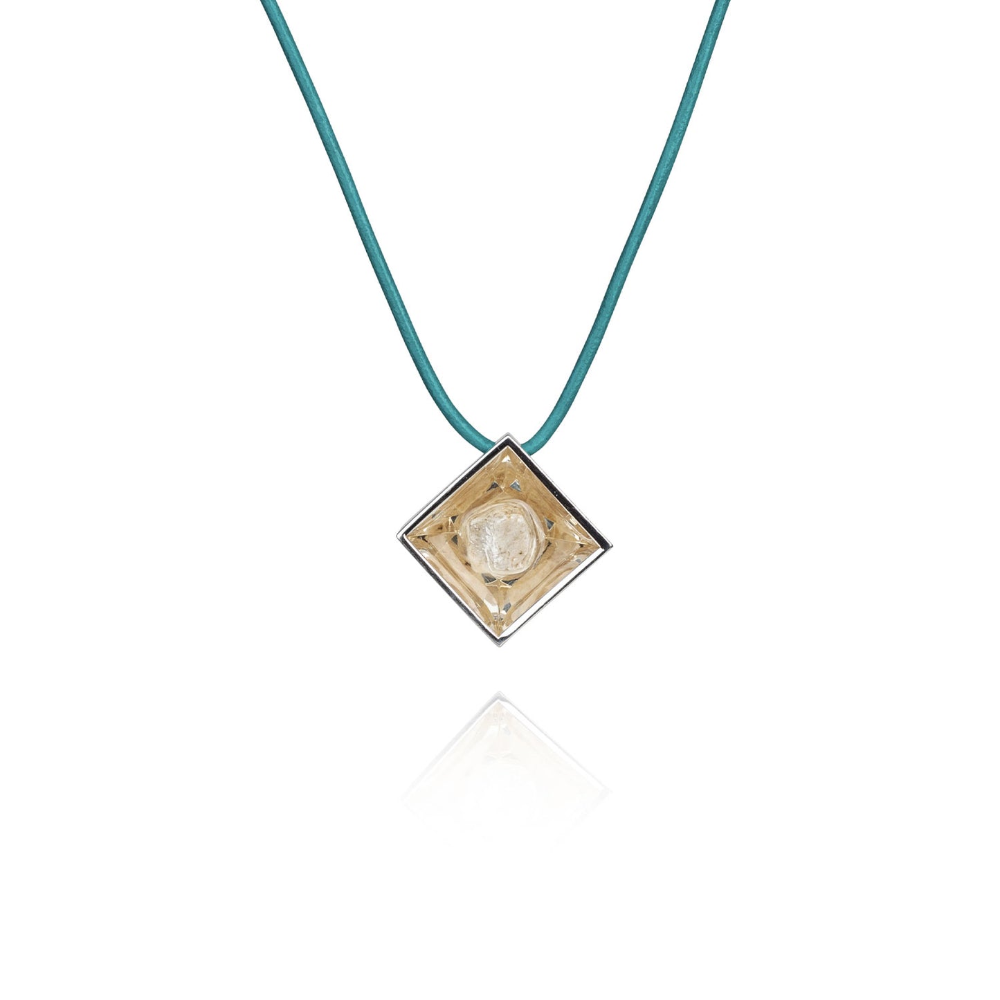 A small natural tan stone sitting in the middle of a diamond shaped metal pendant in a silver color. The pendant is hanging on a turquoise leather necklace.