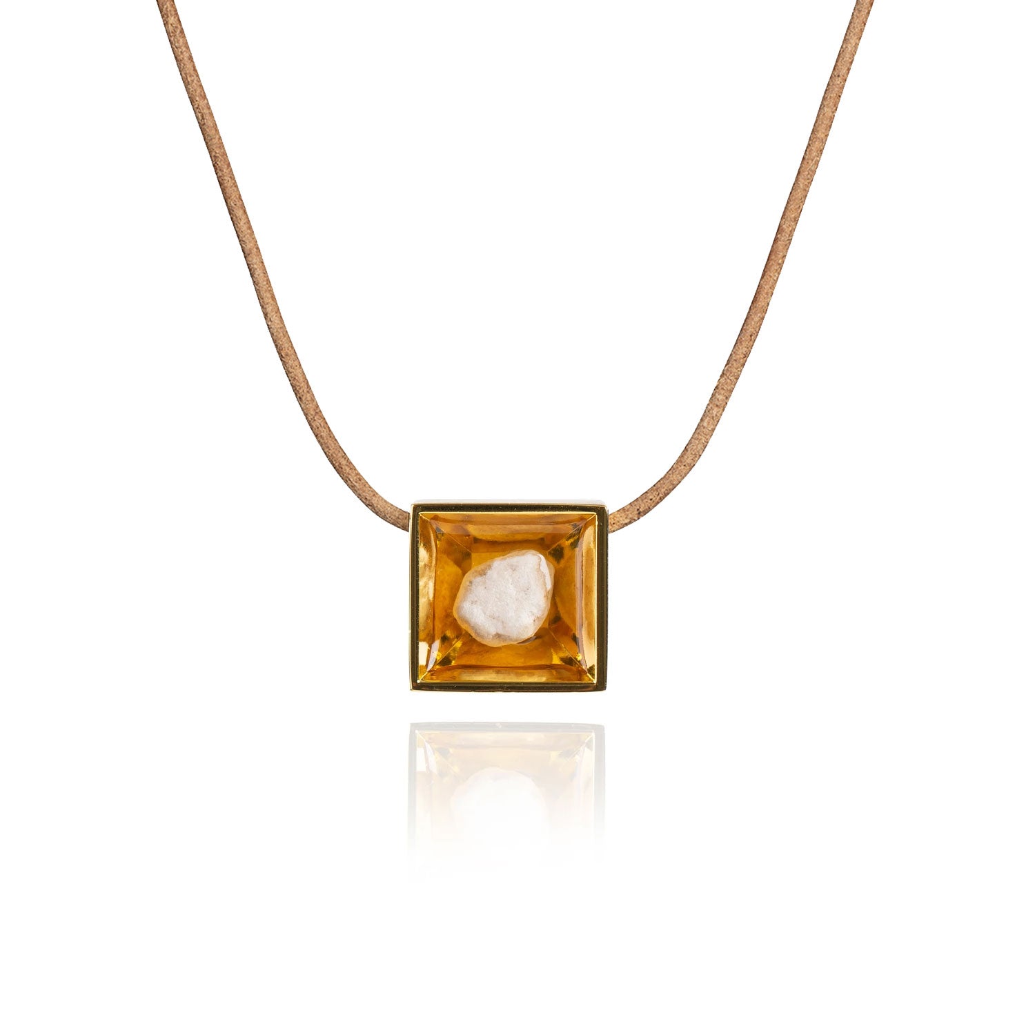A small natural tan stone sitting in the middle of a square shaped metal pendant in a gold color. The pendant is hanging on a tan leather necklace.